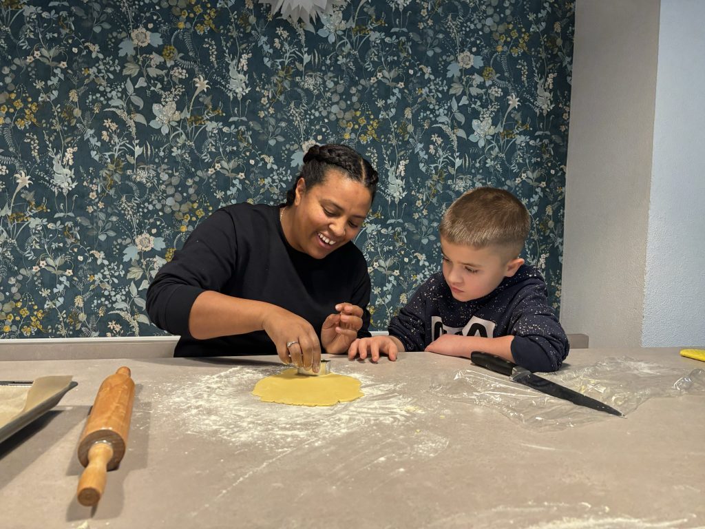 Pedagogin backt zusammen mit Kind einen Teig